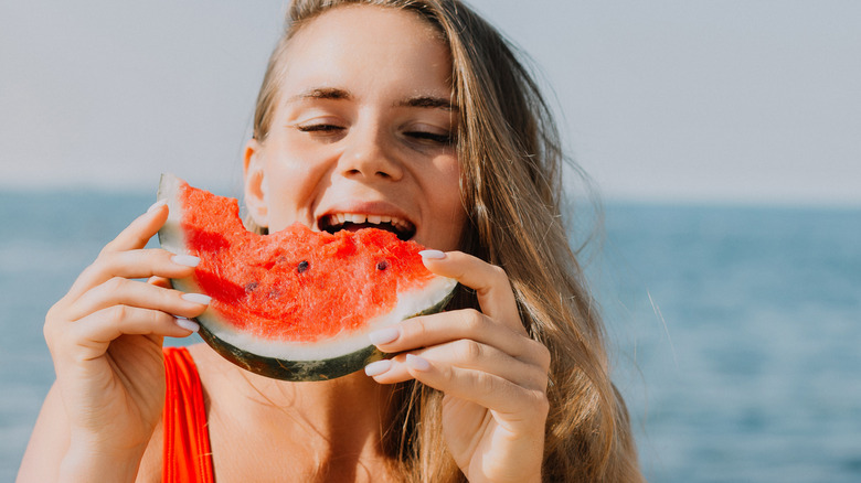 Person eating watermelon at beach