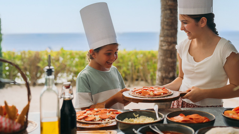 Two kids making a pizza together at a tropical location